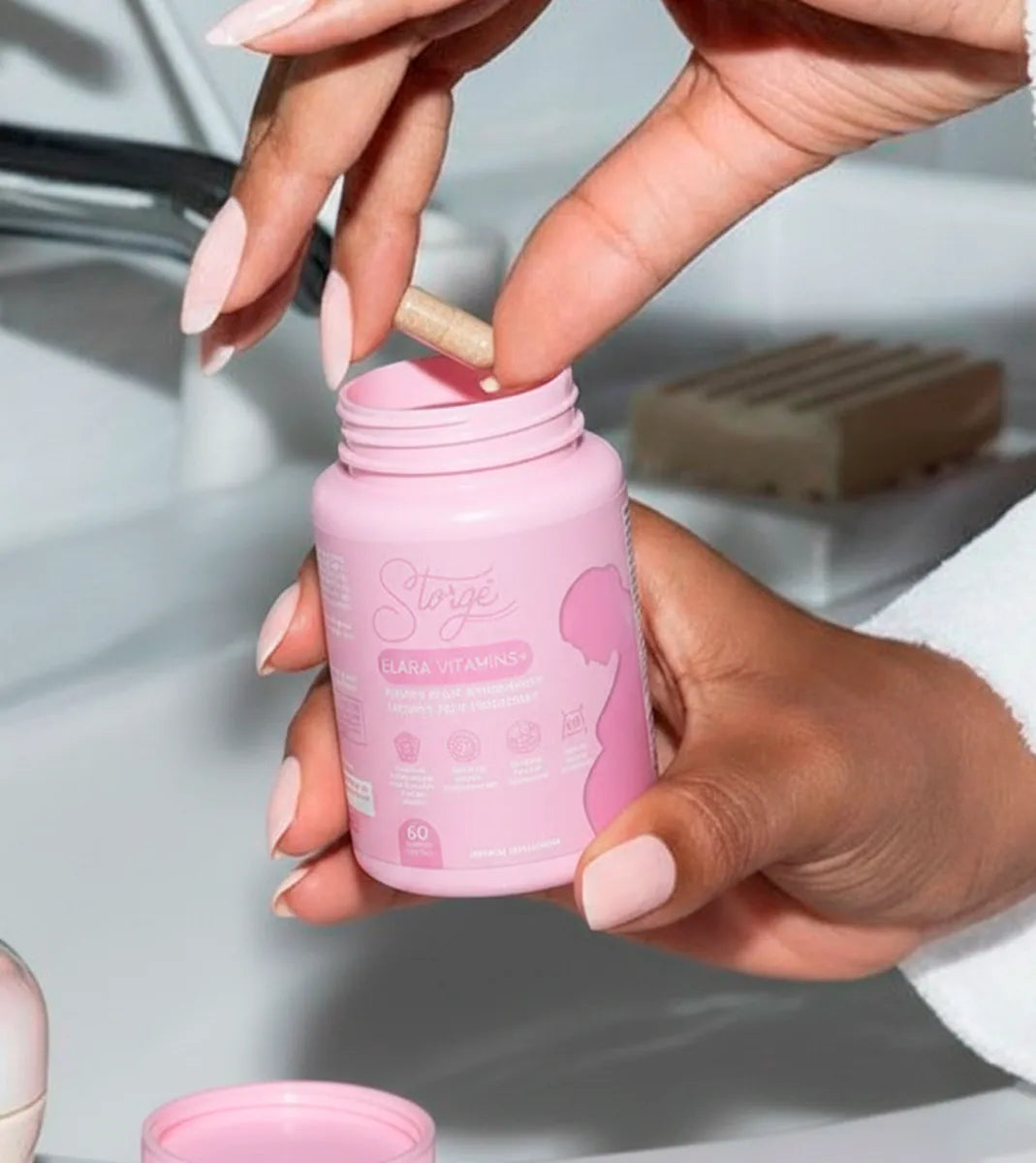 Close up of woman taking capsule from Storgé Elara prenatal vitamins jar, daily supplement routine