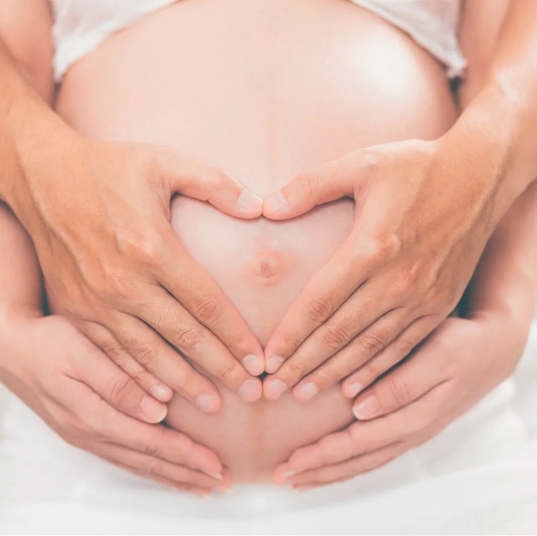 Couple forming heart shape with hands on pregnant belly, loving maternity lifestyle moment