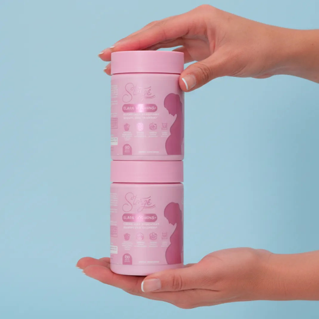 Hands holding stacked Storgé Elara prenatal vitamins containers, modern maternity supplement branding