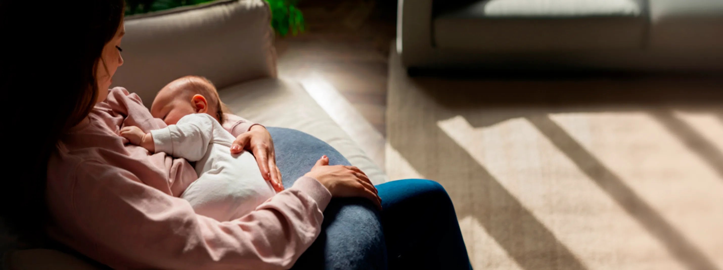Mother breastfeeding newborn baby in cozy living room, postpartum bonding and maternal care moment