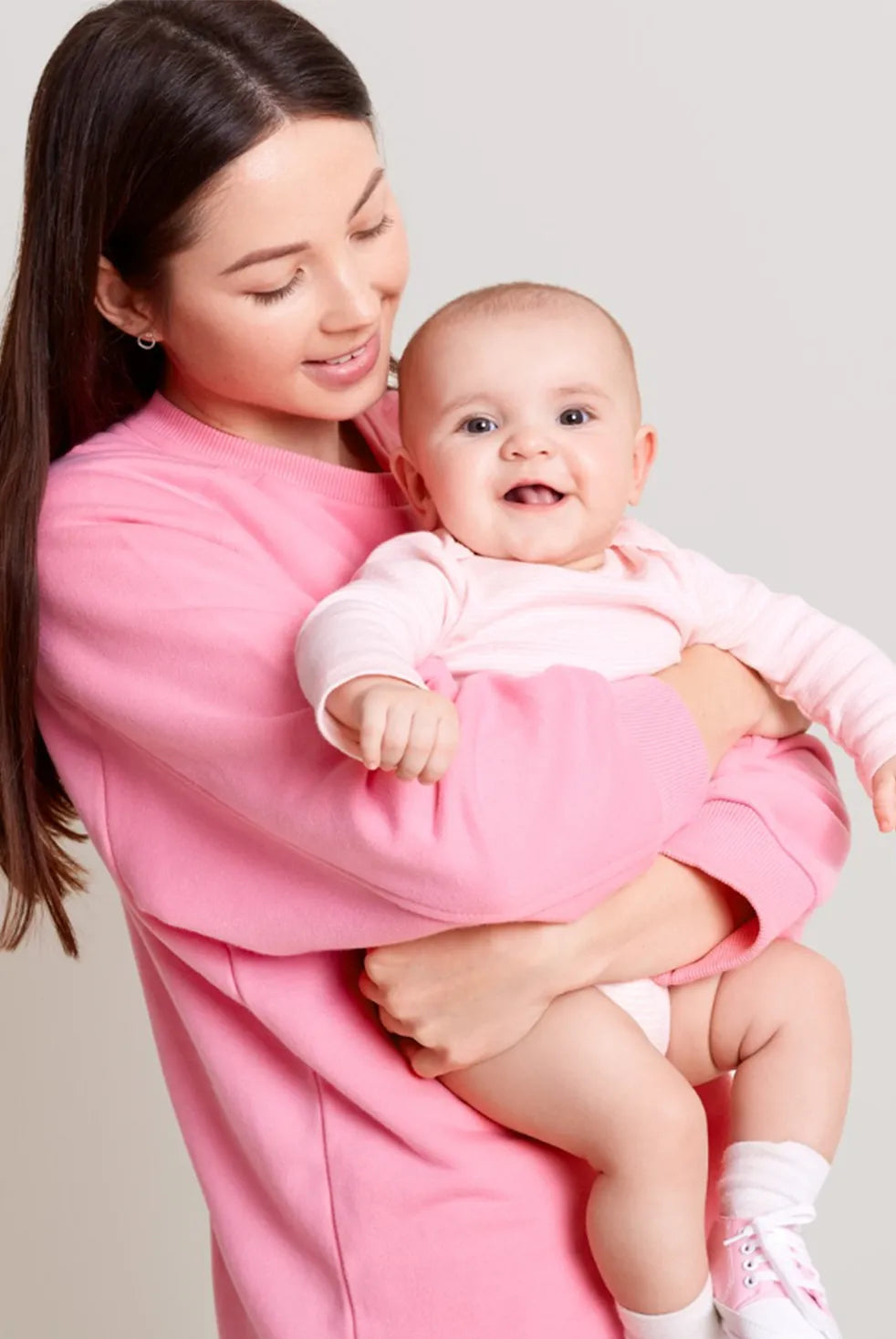 Mother holding baby in pink outfit, postpartum motherhood lifestyle inspired by prenatal vitamins brand