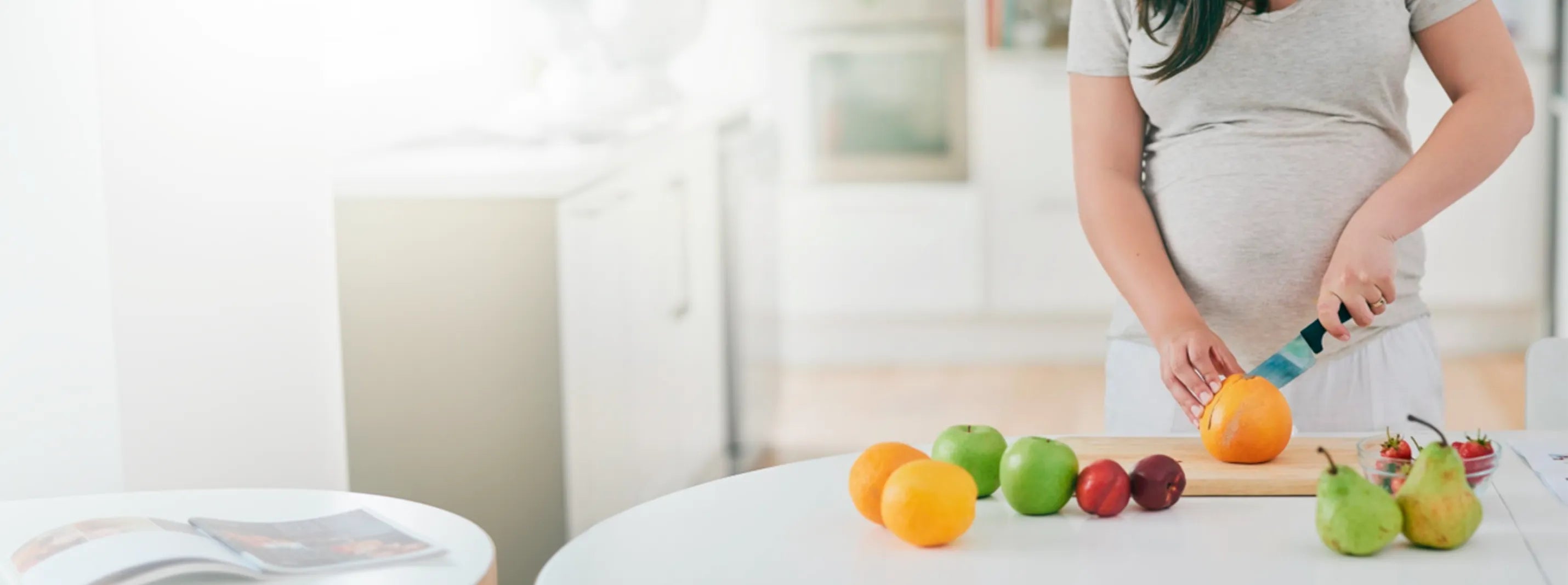 Pregnant woman preparing fresh fruit in kitchen, clean eating and pregnancy wellness lifestyle