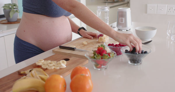 Pregnant woman preparing fresh fruit in kitchen, healthy pregnancy nutrition and balanced maternity lifestyle