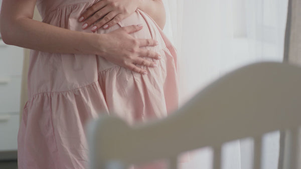 Pregnant woman gently holding her baby bump at home, peaceful maternity lifestyle moment